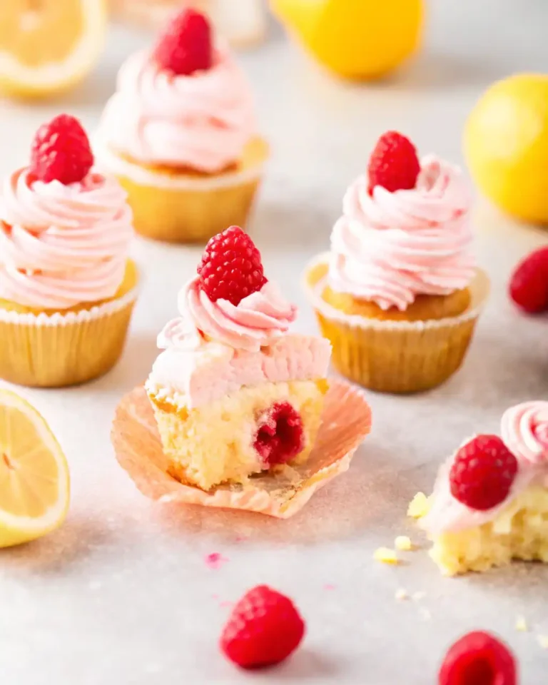 A raspberry-lemon cupcake with a bite taken out, revealing raspberry jam inside.