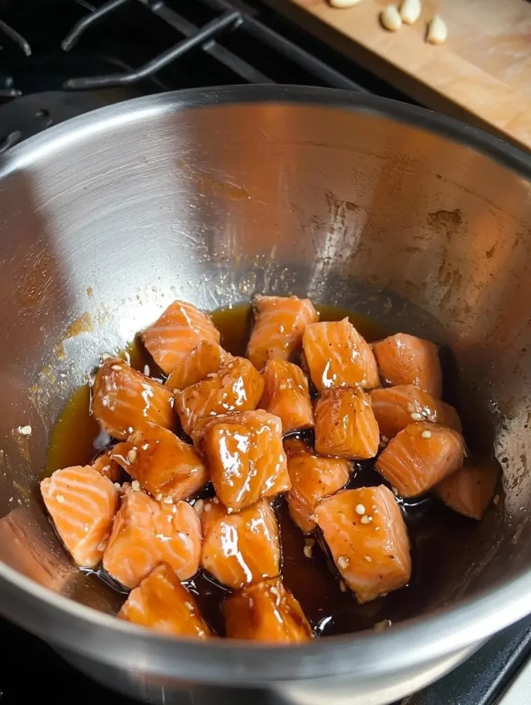 Salmon cubes marinated in soy sauce and seasoning in a silver bowl.