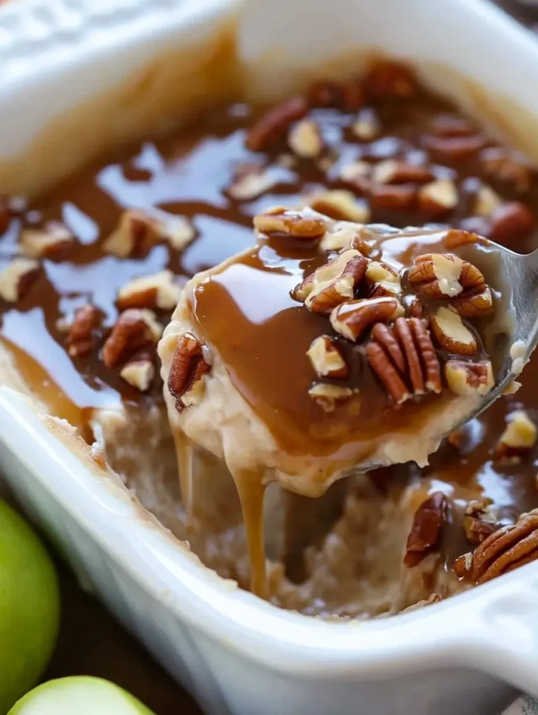 A spoon lifting a serving of dessert with caramel sauce and pecans.